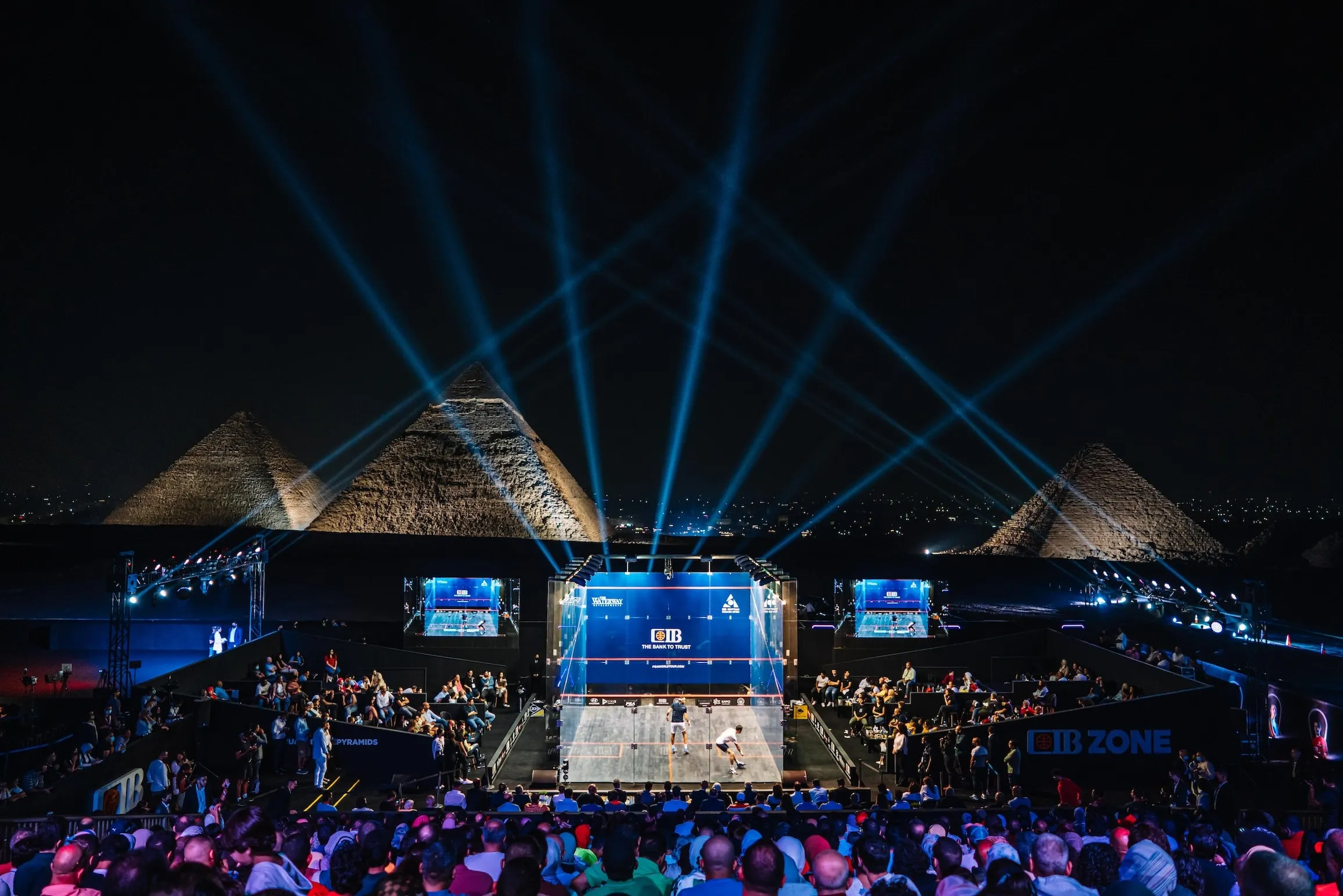 Glass court lit up in front of the Pyramids of Giza